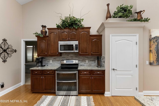 kitchen featuring appliances with stainless steel finishes, light hardwood / wood-style floors, backsplash, and dark brown cabinetry