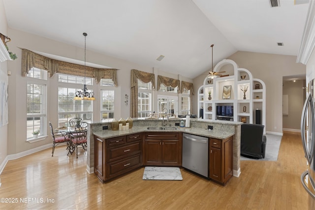 kitchen featuring ceiling fan with notable chandelier, appliances with stainless steel finishes, an island with sink, sink, and light hardwood / wood-style flooring