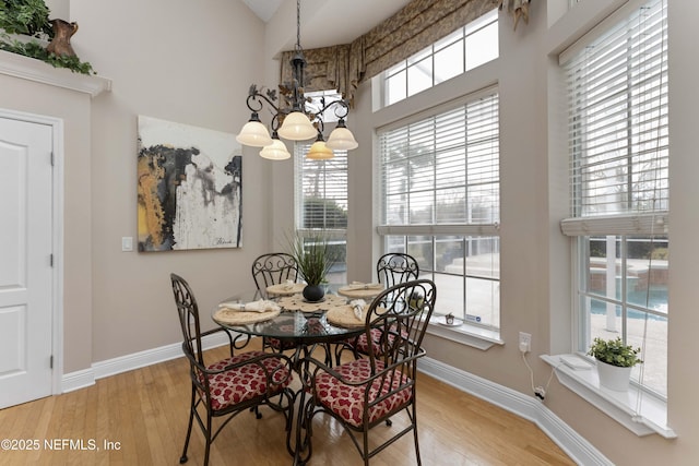 dining area with light wood-type flooring, a chandelier, and a healthy amount of sunlight