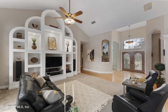 living room with ceiling fan, built in features, french doors, and high vaulted ceiling