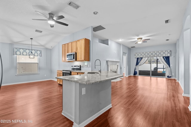 kitchen with appliances with stainless steel finishes, pendant lighting, sink, light stone counters, and kitchen peninsula