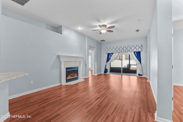 unfurnished living room featuring a tiled fireplace, ceiling fan, and light hardwood / wood-style floors