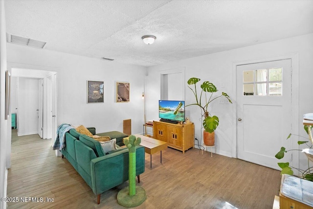 living room featuring a textured ceiling and light wood-type flooring