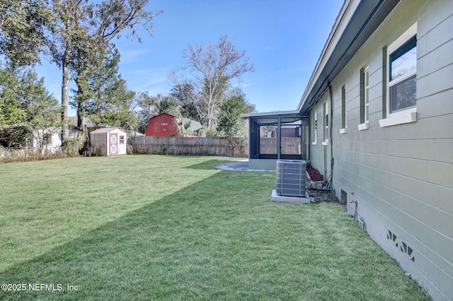 view of yard featuring a sunroom, central air condition unit, and a storage unit