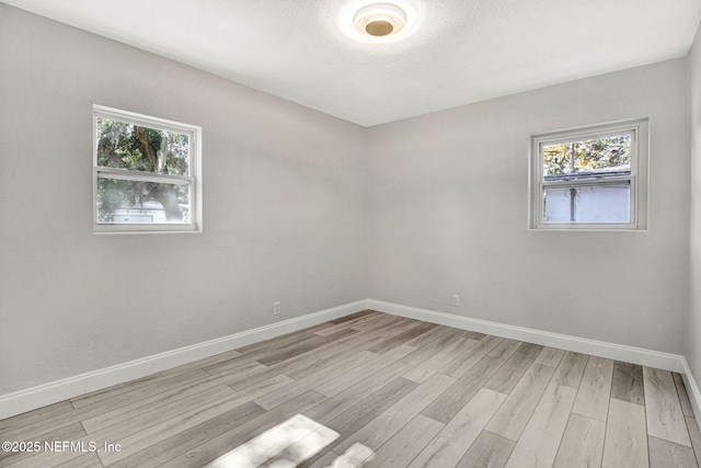 unfurnished room featuring a textured ceiling and light hardwood / wood-style floors