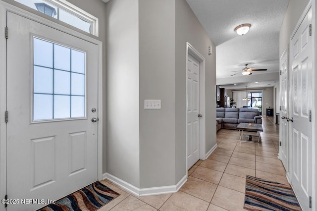 foyer featuring light tile patterned flooring, ceiling fan, and a textured ceiling