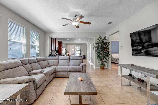 tiled living room with ceiling fan and a textured ceiling