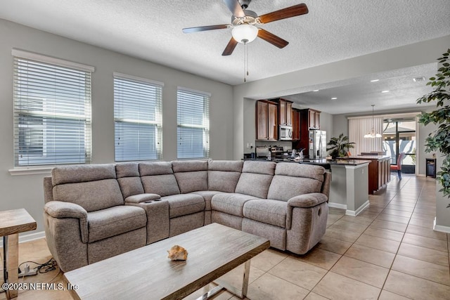 living room with ceiling fan with notable chandelier, a textured ceiling, and light tile patterned floors