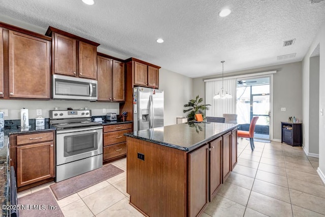 kitchen featuring pendant lighting, appliances with stainless steel finishes, a center island, and light tile patterned floors