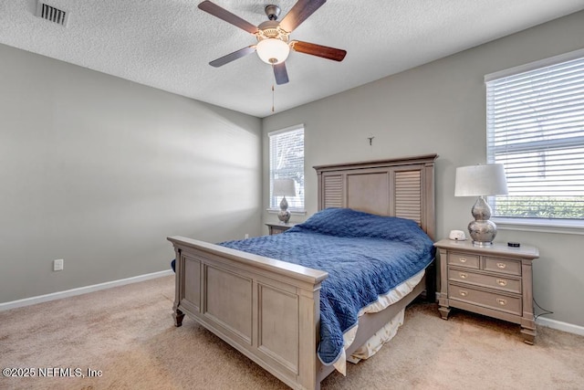 bedroom featuring ceiling fan, light colored carpet, and a textured ceiling