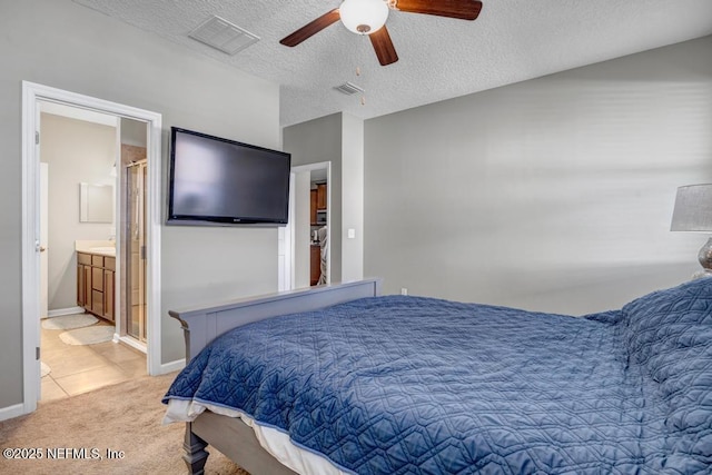 bedroom featuring light carpet, ceiling fan, a textured ceiling, and ensuite bathroom