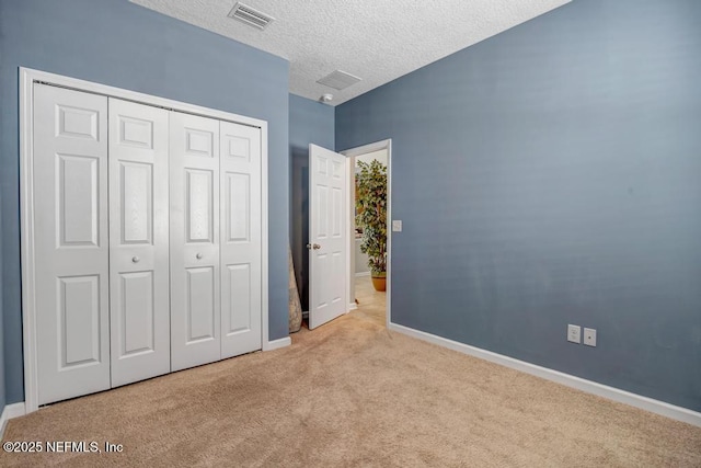 unfurnished bedroom with light colored carpet, a closet, and a textured ceiling