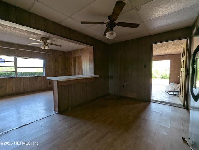 interior space featuring light wood-type flooring, a paneled ceiling, and wooden walls