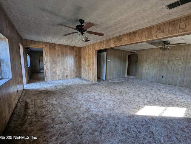 interior space featuring ceiling fan, wooden walls, and carpet flooring