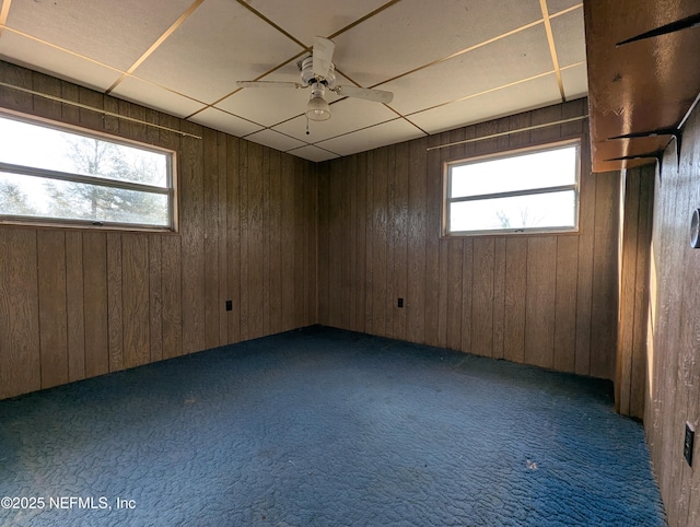 carpeted empty room featuring ceiling fan and wood walls