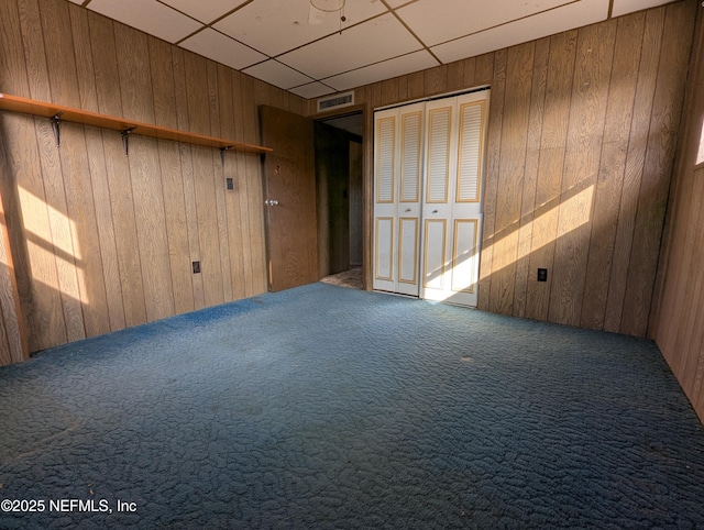 carpeted spare room with wood walls