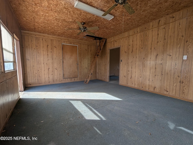 empty room with ceiling fan and wood walls