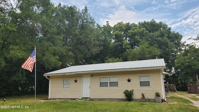 view of front of property with metal roof and a front yard