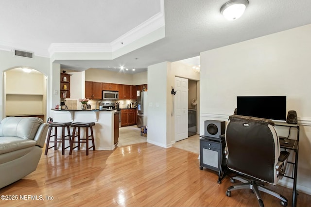 office space featuring ornamental molding, light hardwood / wood-style flooring, and a textured ceiling