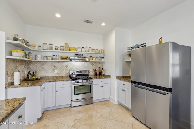 kitchen with white cabinetry, stainless steel appliances, extractor fan, and dark stone countertops