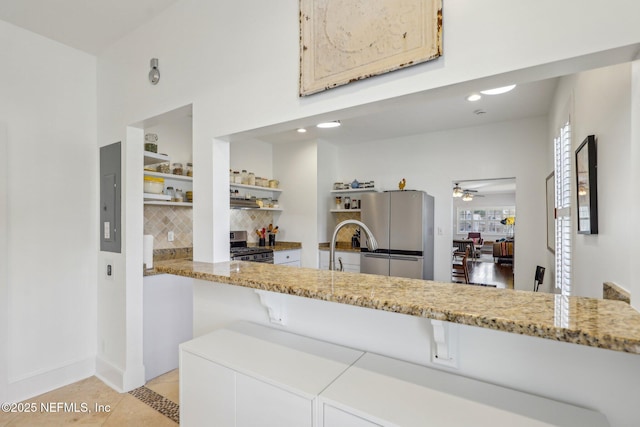 kitchen featuring ceiling fan, electric panel, light tile patterned floors, decorative backsplash, and stainless steel appliances