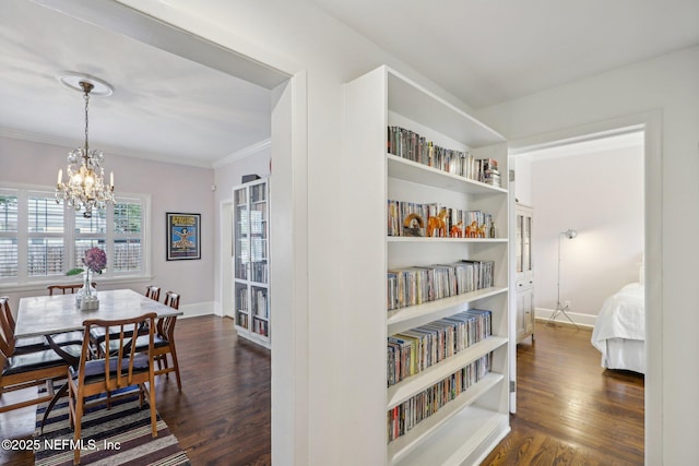 interior space featuring dark hardwood / wood-style floors, ornamental molding, and a notable chandelier