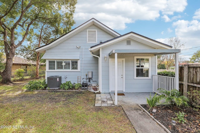 rear view of house featuring a lawn, a porch, and central air condition unit