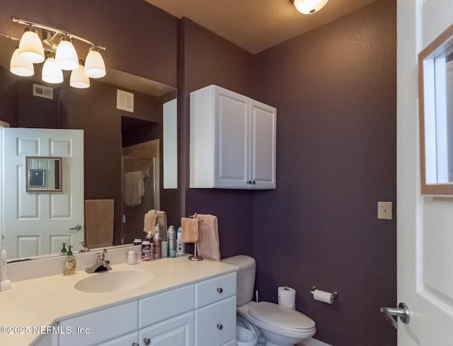 bathroom with toilet, vanity, and a shower with shower door