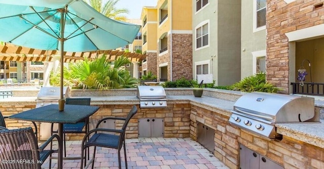 view of patio / terrace with exterior kitchen, a pergola, and grilling area