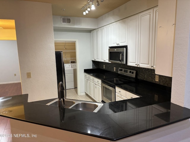 kitchen with kitchen peninsula, stainless steel appliances, backsplash, track lighting, and white cabinets