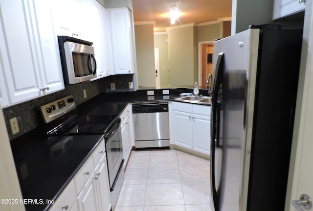 kitchen with white cabinets, light tile patterned floors, stainless steel appliances, and ornamental molding