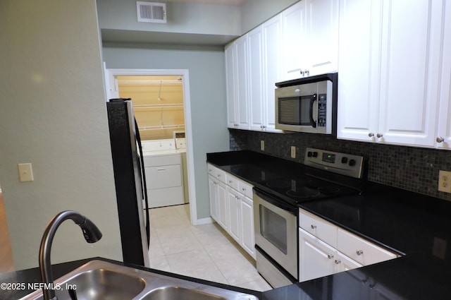 kitchen with appliances with stainless steel finishes, separate washer and dryer, and white cabinetry