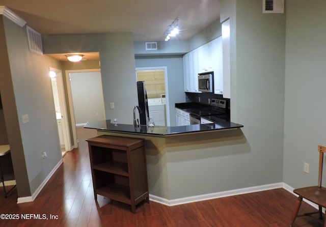 kitchen featuring kitchen peninsula, appliances with stainless steel finishes, decorative backsplash, dark hardwood / wood-style floors, and white cabinets