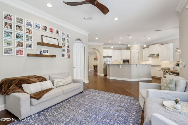 living room featuring dark hardwood / wood-style flooring, ornamental molding, and ceiling fan