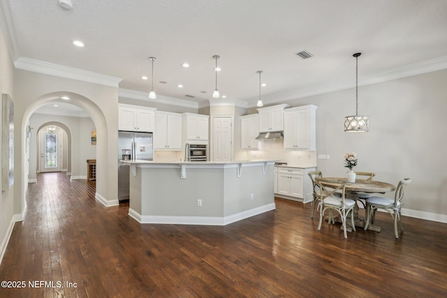 kitchen featuring hanging light fixtures, appliances with stainless steel finishes, dark hardwood / wood-style flooring, a large island, and white cabinets