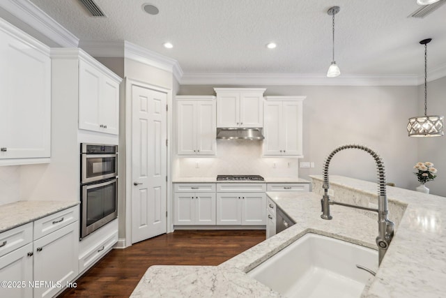 kitchen featuring pendant lighting, light stone countertops, and appliances with stainless steel finishes