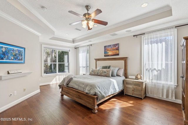 bedroom featuring crown molding, a tray ceiling, hardwood / wood-style floors, and a textured ceiling