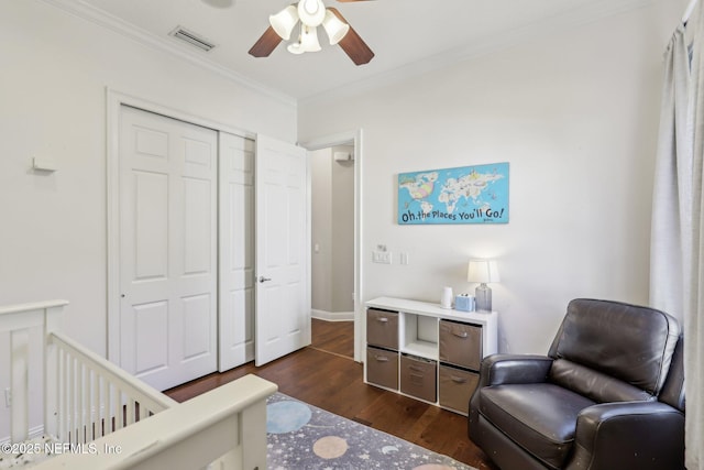 bedroom with crown molding, dark hardwood / wood-style floors, ceiling fan, and a closet