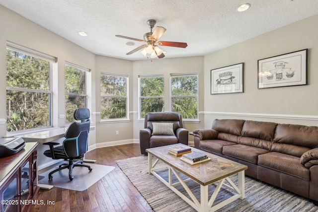 living room featuring ceiling fan, hardwood / wood-style flooring, and a textured ceiling