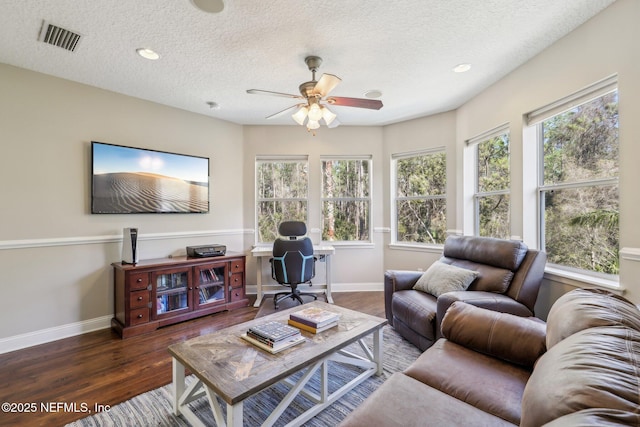 living room featuring dark wood-type flooring, ceiling fan, and a textured ceiling