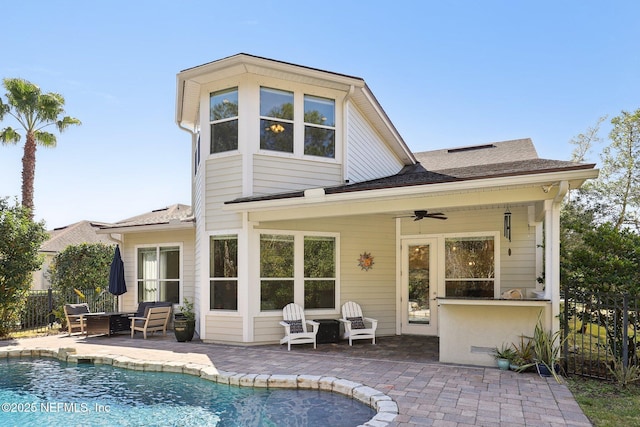 back of property featuring a bar, ceiling fan, a fenced in pool, and a patio