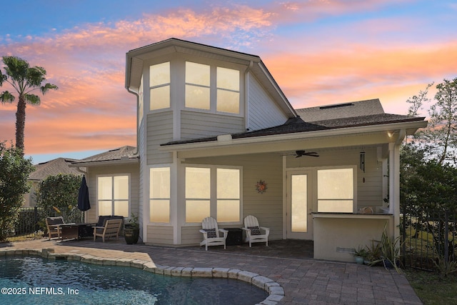 back house at dusk with ceiling fan and a patio area