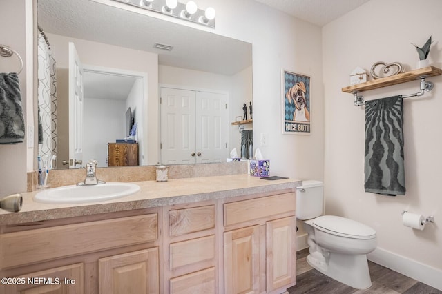 bathroom featuring hardwood / wood-style flooring, a textured ceiling, toilet, and vanity