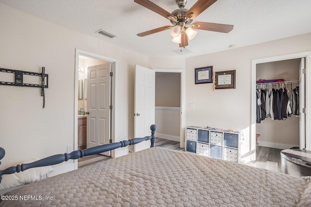 unfurnished bedroom with a textured ceiling, a closet, ceiling fan, ensuite bathroom, and light hardwood / wood-style flooring