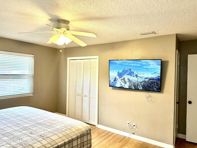 bedroom featuring ceiling fan, a closet, a textured ceiling, and wood-type flooring