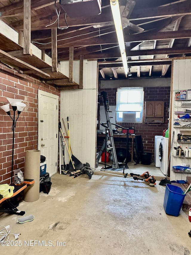 basement featuring separate washer and dryer and brick wall