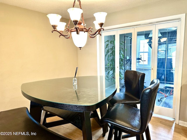 dining room with light hardwood / wood-style floors, a chandelier, and french doors