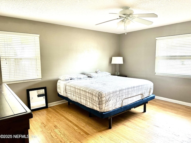 bedroom with a textured ceiling, ceiling fan, and light hardwood / wood-style flooring