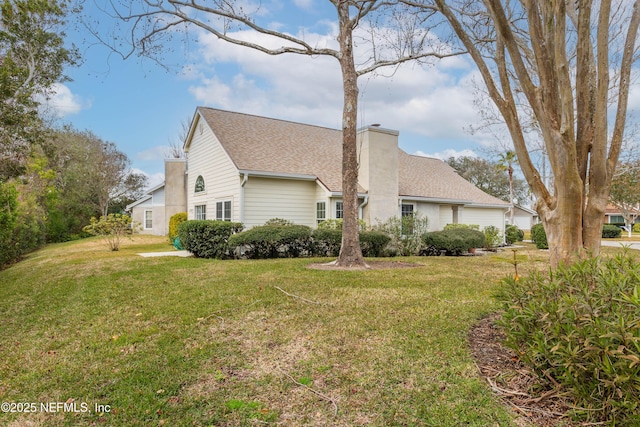 view of side of home with a yard, a chimney, and a shingled roof