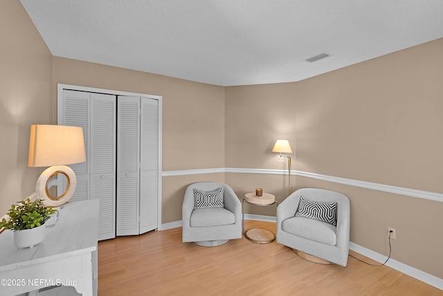 living area featuring wood-type flooring and a textured ceiling